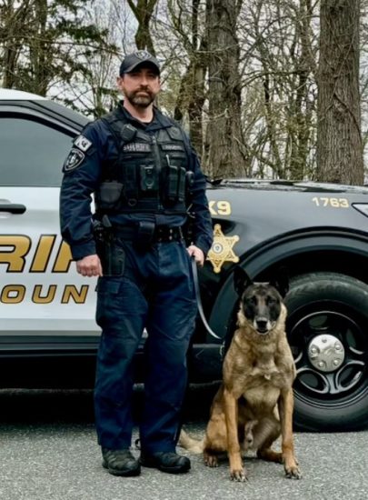 Officer with K9 standing outside next to car